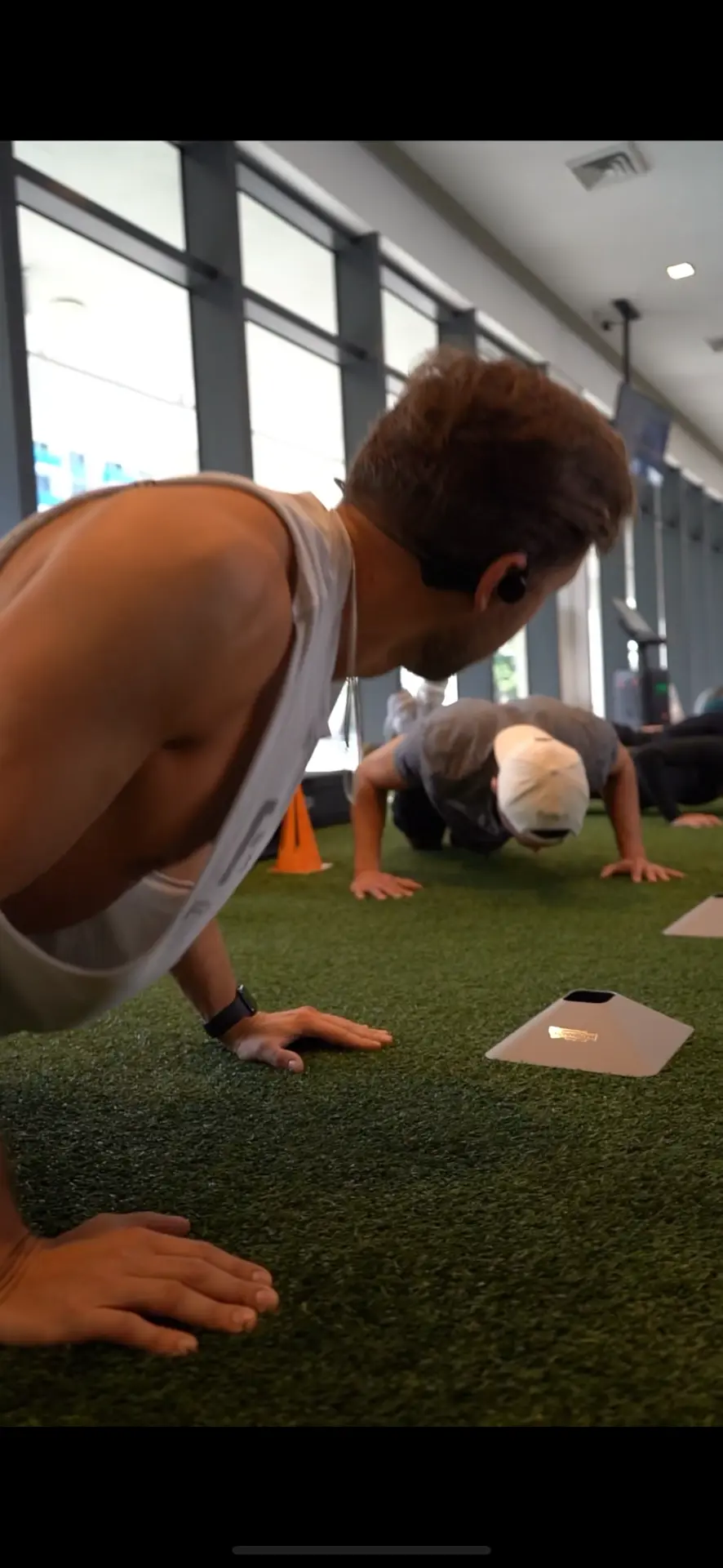 Anthony Perri demonstrating push-ups alongside clients during a class